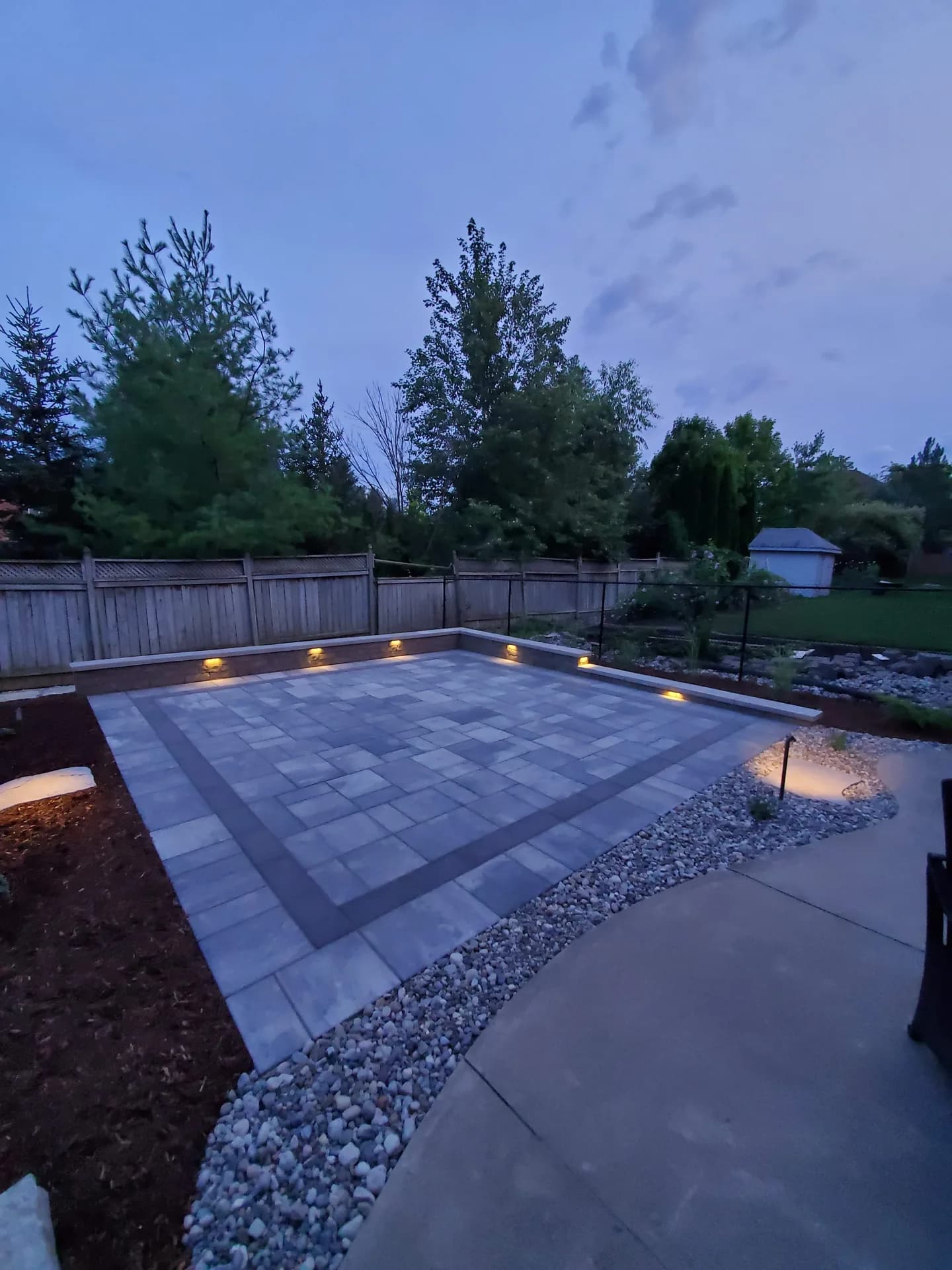 Outdoor landscape lighting on a Hamilton backyard patio with retaining wall cap lights glowing at dusk