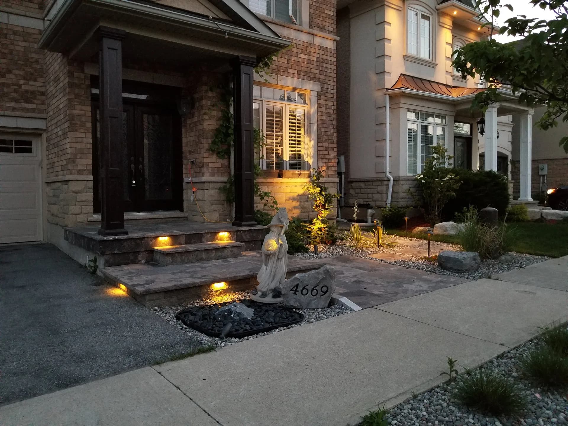 Landscape lighting design at a Hamilton front entrance with step lights, pathway bollards, and garden uplighting at twilight