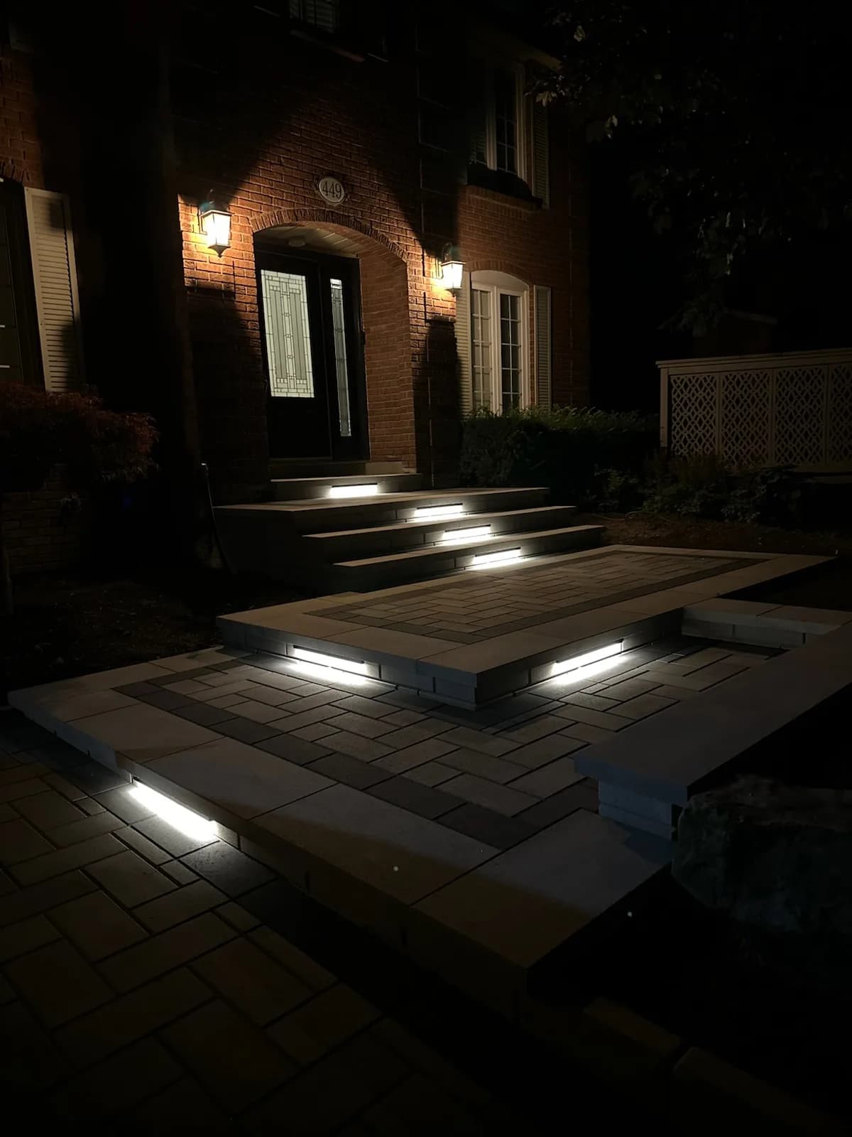 Landscape lighting installation with integrated step lights on interlock stairs and a front walkway in Hamilton at night