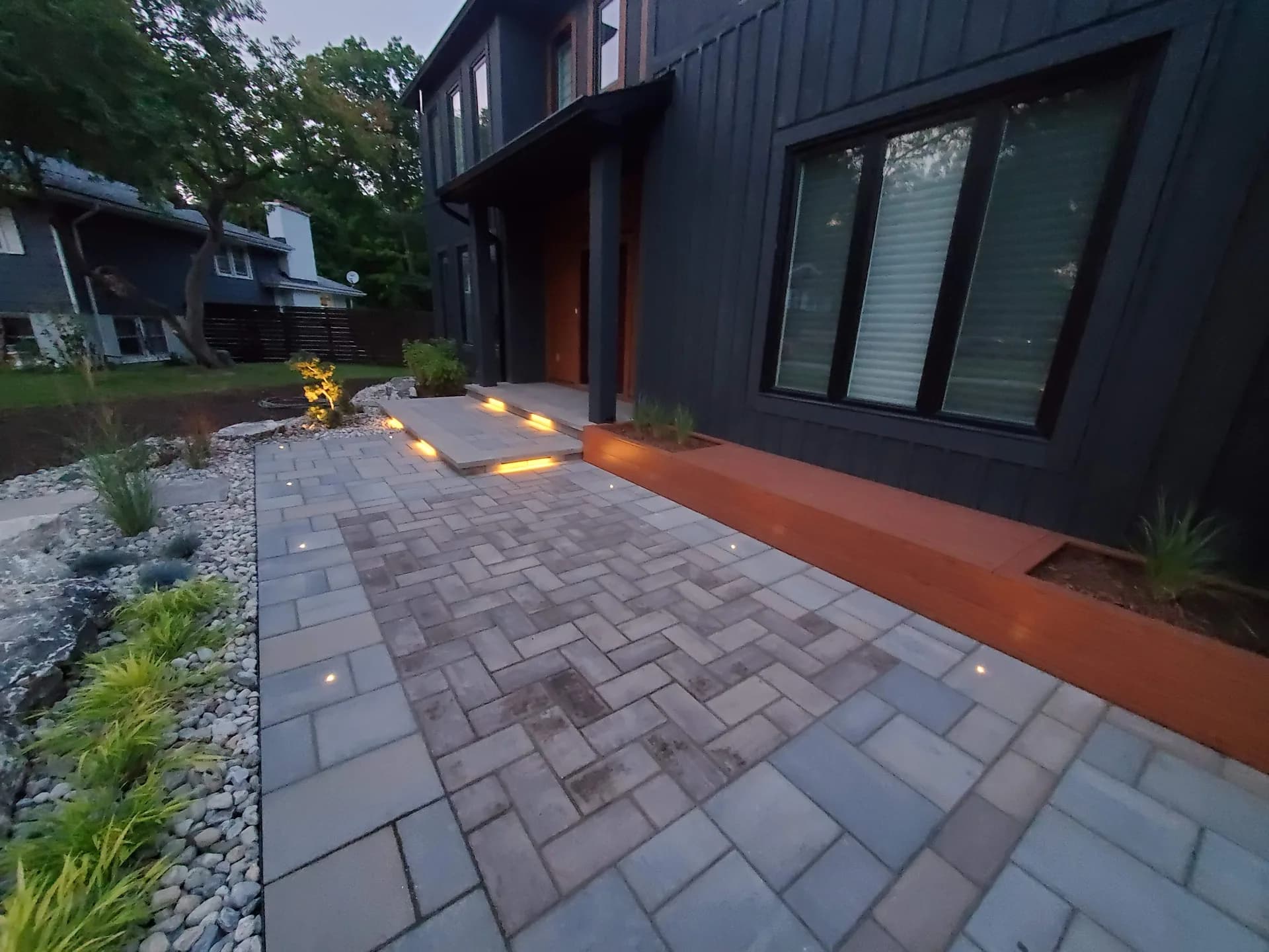 Landscape lighting in Hamilton with LED step lights, recessed paver path lights, and garden uplighting along a front walkway at dusk