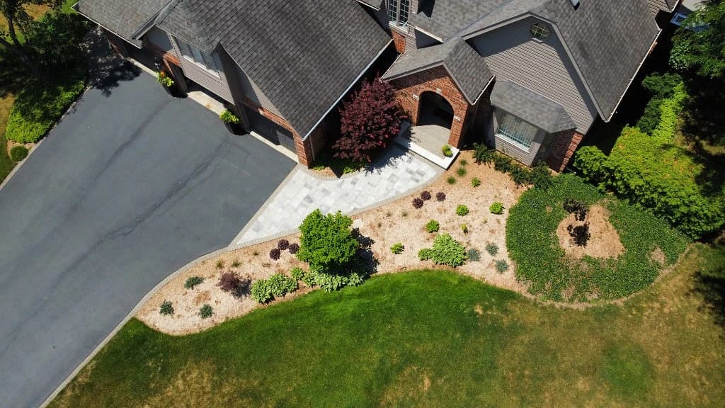 Aerial view of a landscaped front yard with an interlock walkway, mulched garden beds, and green lawn at a home in Ancaster, Ontario